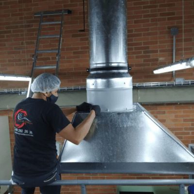 Trabajador instalando un equipo de ventilación en una fábrica industrial.